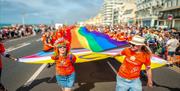 Image courtesy of Jim Carey. Pride revelers carrying a large Pride flag through the streets of Brighton to mark the start of the parade.