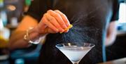 Bar staff squeezing a lemon over a cocktail.
