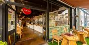 Outside of the restaurant, a Foodilic sign hangs in a doorway with real wooden furniture outside
