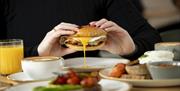 Breakfast bap with egg and delicious looking breakfast items on a table at One Kitchen.m