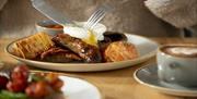 A diner cutting into a plate of a cooked breakfast at One Kitchen