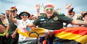 Image courtesy of Jim Carey. A really excited group of people jumping in front of the camera waving Pride flags