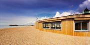 Outside shot of the Yellowave Beach House, a wooden structure with sand outside.