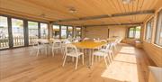 Inside shot of the Yellowave Beach House, a panelled room with sea views, with seating laid out around a table.