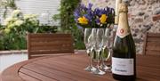 Bottle of fizz and glasses on a table.