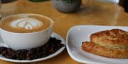 A cup of coffee sits alongside a pastry treat.