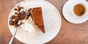A slice of chocolate cake with a coffee.