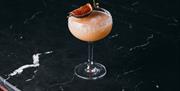 Cocktail on the bar with a fig slice on the top.