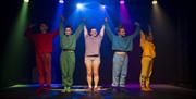Image courtesy of dfphotography. Performers take a bow at Absurd Tea Circus in 2024, they are wearing colourful tracksuits.