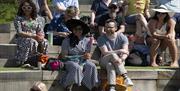 Image courtesy of dfphotography. A Locomotive for Murder show from 2024. 2 audience members at Brighton Open Air Theatre enjoying the show.