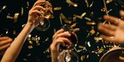 Image shows guests celebrating at a Joiner Christmas party at DoubleTree by Hilton Brighton Metropole. Champagne flutes are raised in the air whilst g