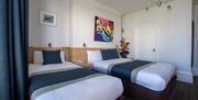 Twin single beds at The New Steine hotel with beautiful vibrant pictures in the background.