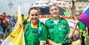 Image courtesy of Jim Carey. Two people wearing ambulance uniforms carrying the Pride flags