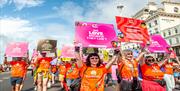 Image courtesy of Jim Carey. Pride Parade attendees wearing bright orange tops carrying signs which read "We Love Because They Can't"
