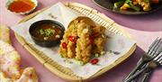 Bamboo dish with tempura and a dipping sauce on the side.