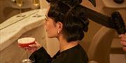 A woman with her hair in curlers enjoying a cocktail.