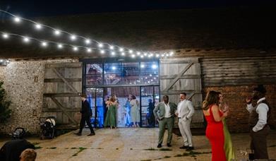 Guests enjoying a party night at Charleston. Image shows guests stood outside the haybarn at Charleston