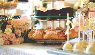 Cupcakes on stand with pink roses and small cakes beside them