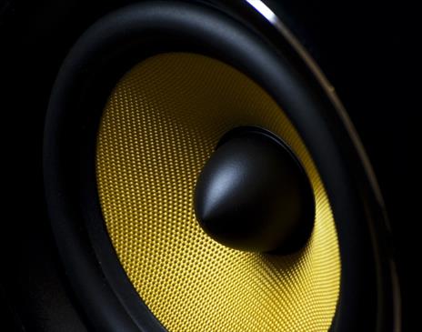 Zoomed in shot of a black speaker with bright yellow mesh