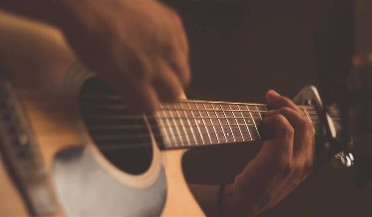 Person playing acoustic guitar with a capo