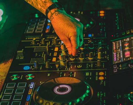 Electric mixing decks being operated by person with tattoos