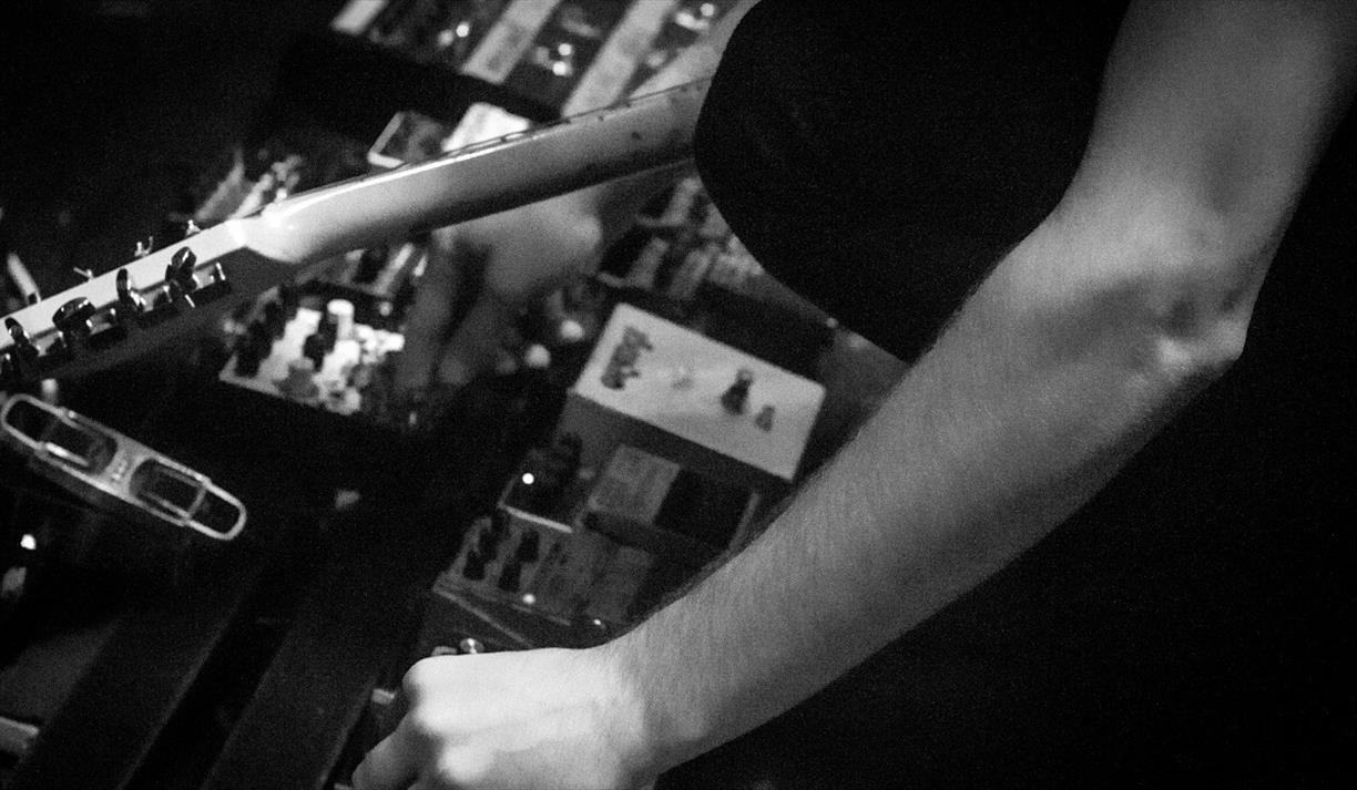 Black and white image of a person working a pedalboard