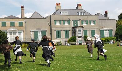Children in historic dress running on lawn 