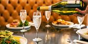 A glass of sparkling wine is being topped up