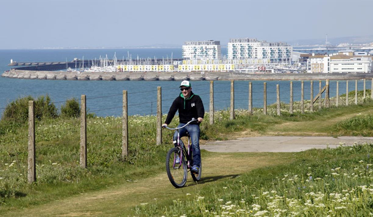 Cyclist on top of cliff with Brighton Marina in background