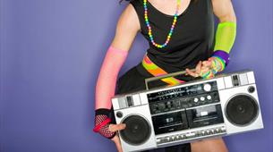 A women wearing bright colourful clothing holding a boom box 