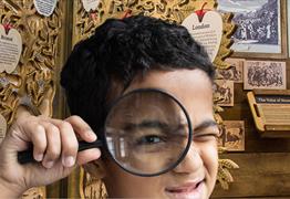 A young boy holding a magnifying glass to his face