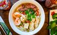 Bowl of pho with noodles, prawns and garnish