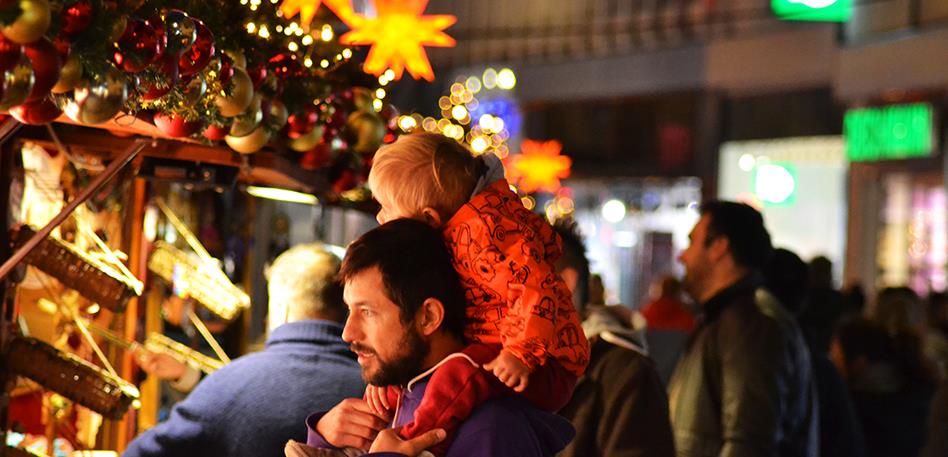 Man with child on shoulders at Christmas market
