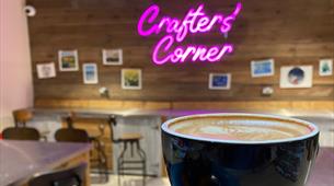 Crafter's Corner neon sign, coffee in front 
