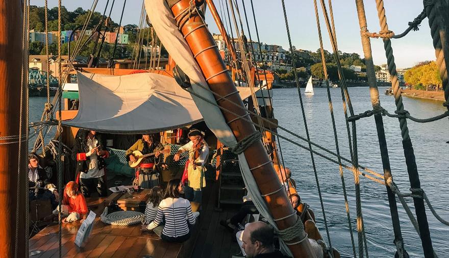 Band called Piratitude perform on The Matthew ship in Bristol Harbour with audience looking on