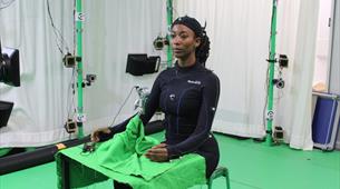 A women wearing all black sat in a green screen room 