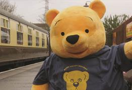 A giant yellow teddy bear on a train platform
