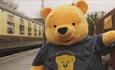 A giant yellow teddy bear on a train platform