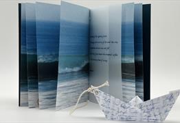 A photo book with an oragami boat in front