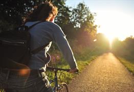 A person cycling on a cycle path at sunset
