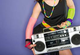 A women wearing bright colourful clothing holding a boom box