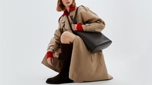 A model posing where a beige trench coat 