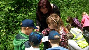 Children and woman looking at trail map in forest