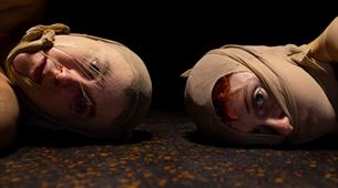 Two people lying on the floor with stockings on their faces