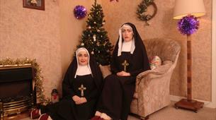 Nuns sat in a living room with Christmas decorations