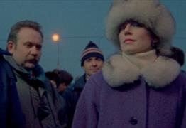 A still from the 1993 film From the East featuring two men and a woman looking towards the camera