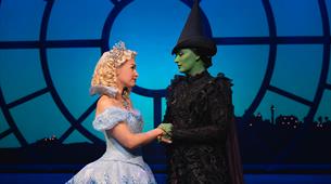 Two witches look at each other in a scene from Wicked