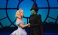 Two witches look at each other in a scene from Wicked