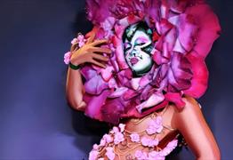 A drag artist with a flower head dress