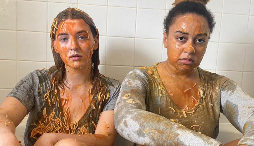 2 girls stat in a bath tub covered in spaghetti